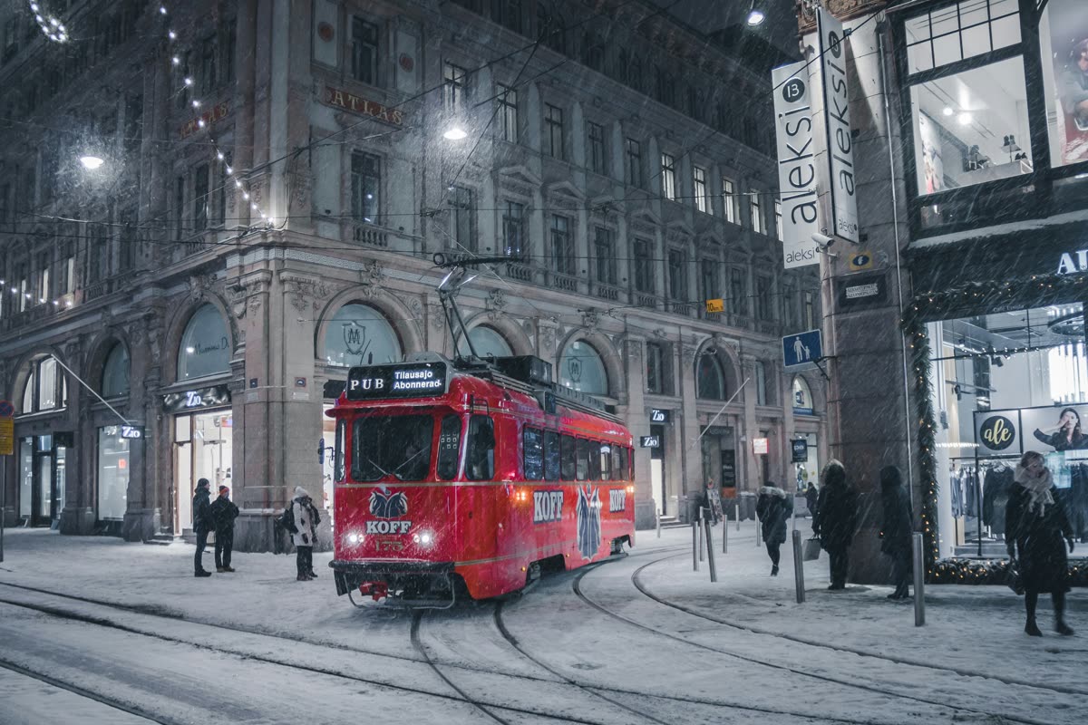 A red tram on a snowy Helsinki street at night
